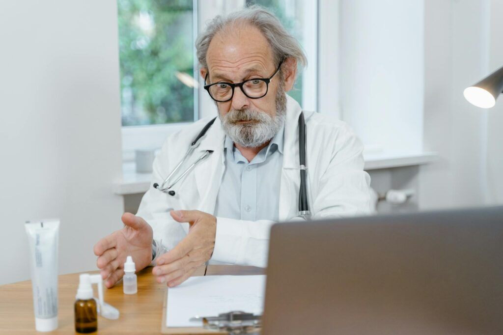 Senior doctor reviewing dizziness and balance concerns during an online care consultation.