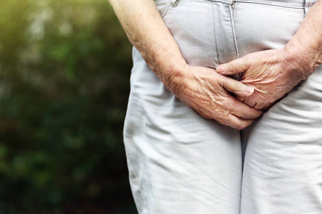 Senior woman holding hands near abdomen, representing pelvic floor therapy and Emsella treatment for urinary incontinence