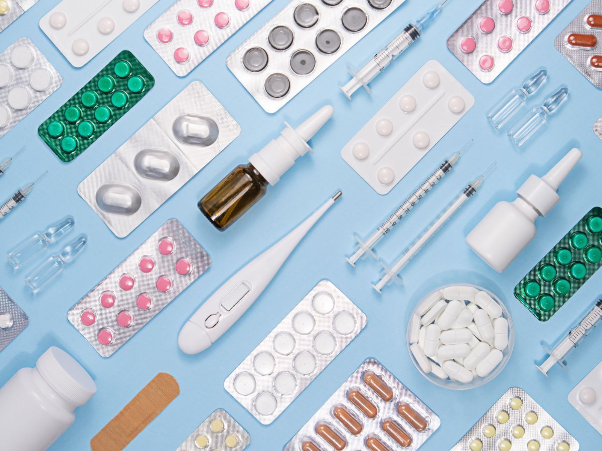 Various medical supplies including pills, syringes, and a thermometer on a blue background.