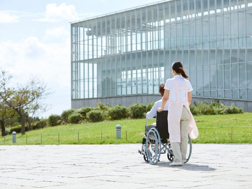 Caregiver walking with senior in wheelchair – assisted living placement for seniors and personalized elder care services in Los Angeles.