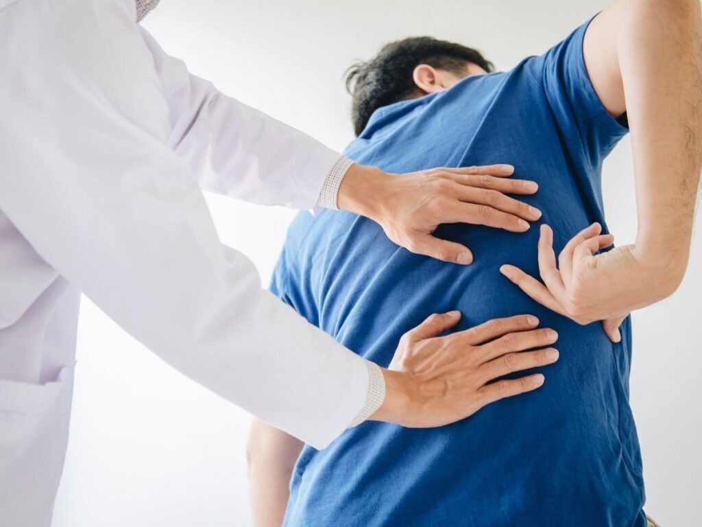 Doctor examining a senior man’s back – back injury treatment and pain relief for seniors in Los Angeles.