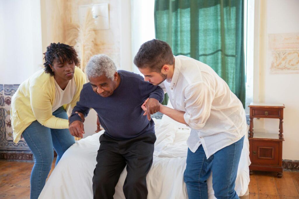 Caregiver supporting an older adult at home with chronic pain and daily function needs.