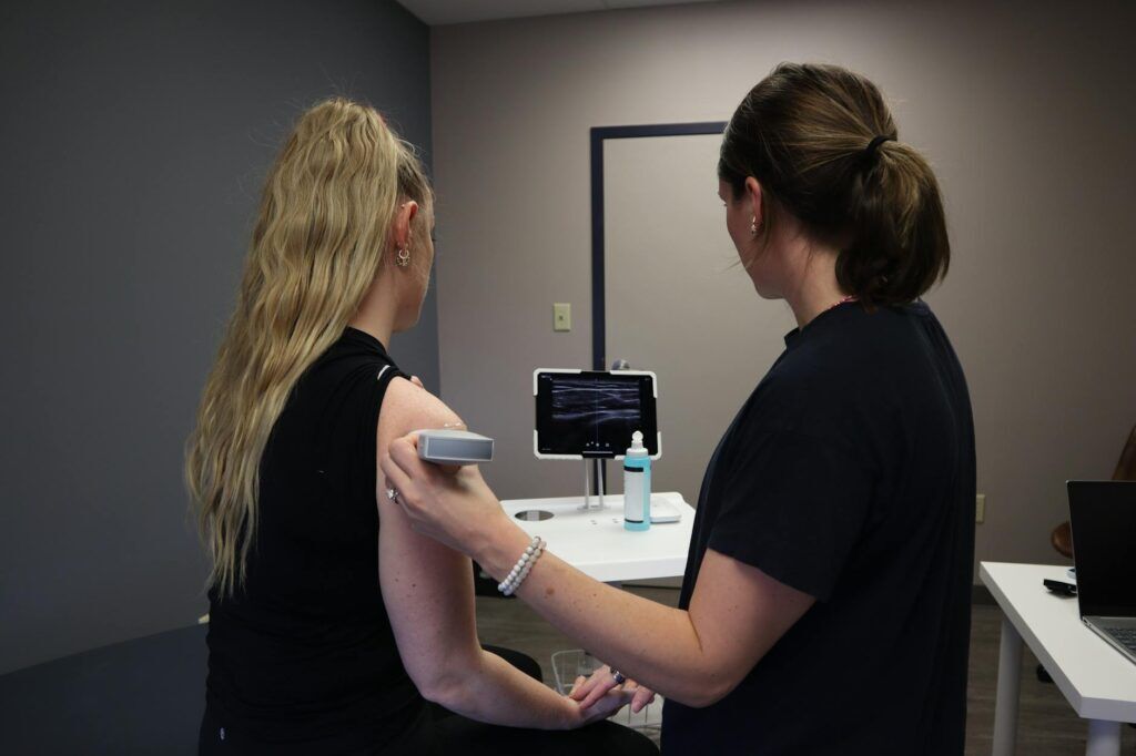 Clinician using ultrasound near the shoulder during evaluation of frozen shoulder symptoms.