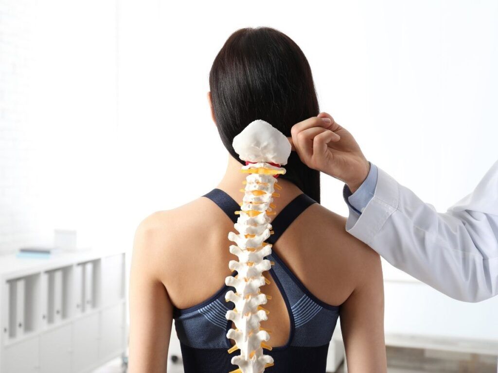 Doctor showing spine model to senior patient – back strain treatment and posture care for seniors in Los Angeles.