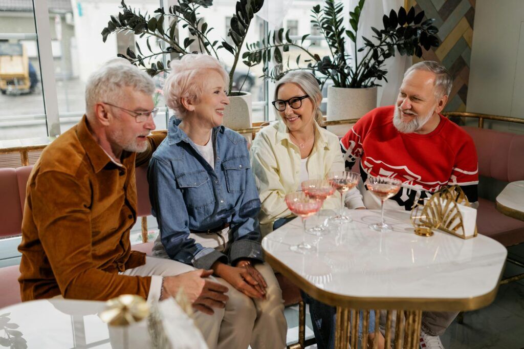 Senior friends gathering at a cafe table, smiling and enjoying coffee, showcasing togetherness and happiness.