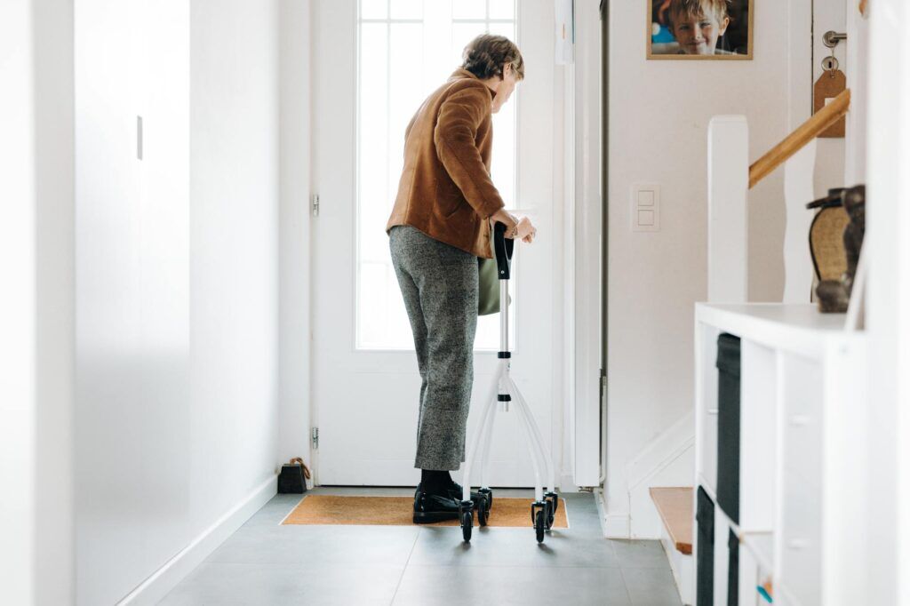Senior adult using a rollator indoors for balance and fall-risk support.